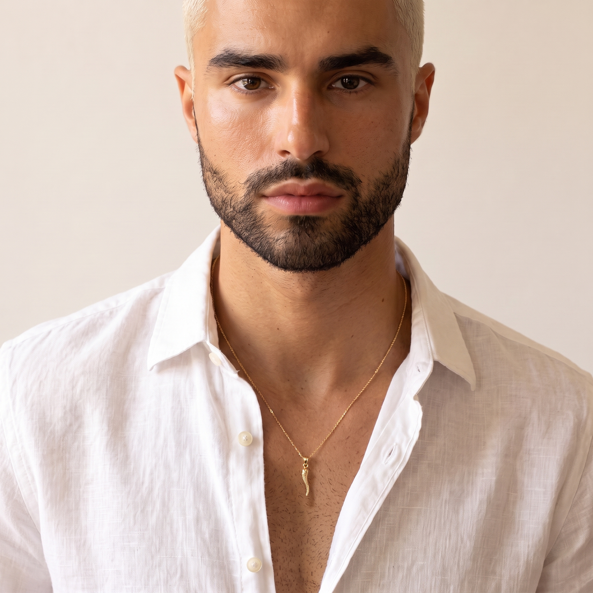 10K yellow gold Italian horn pendant worn by a man with an open-collar shirt