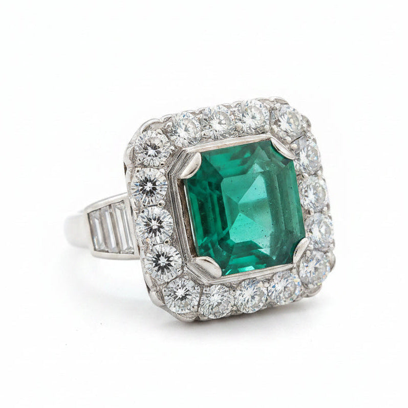 A platinum ring featuring a square-cut green emerald gemstone surrounded by a halo of clear diamonds, with baguette-cut side stones on the band.